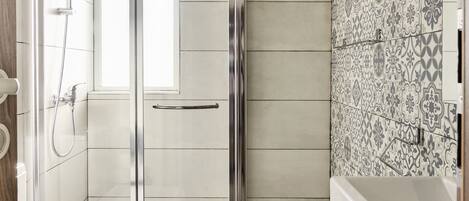 A modern bathroom with a glass-enclosed shower, a white toilet, and a patterned tile backsplash.