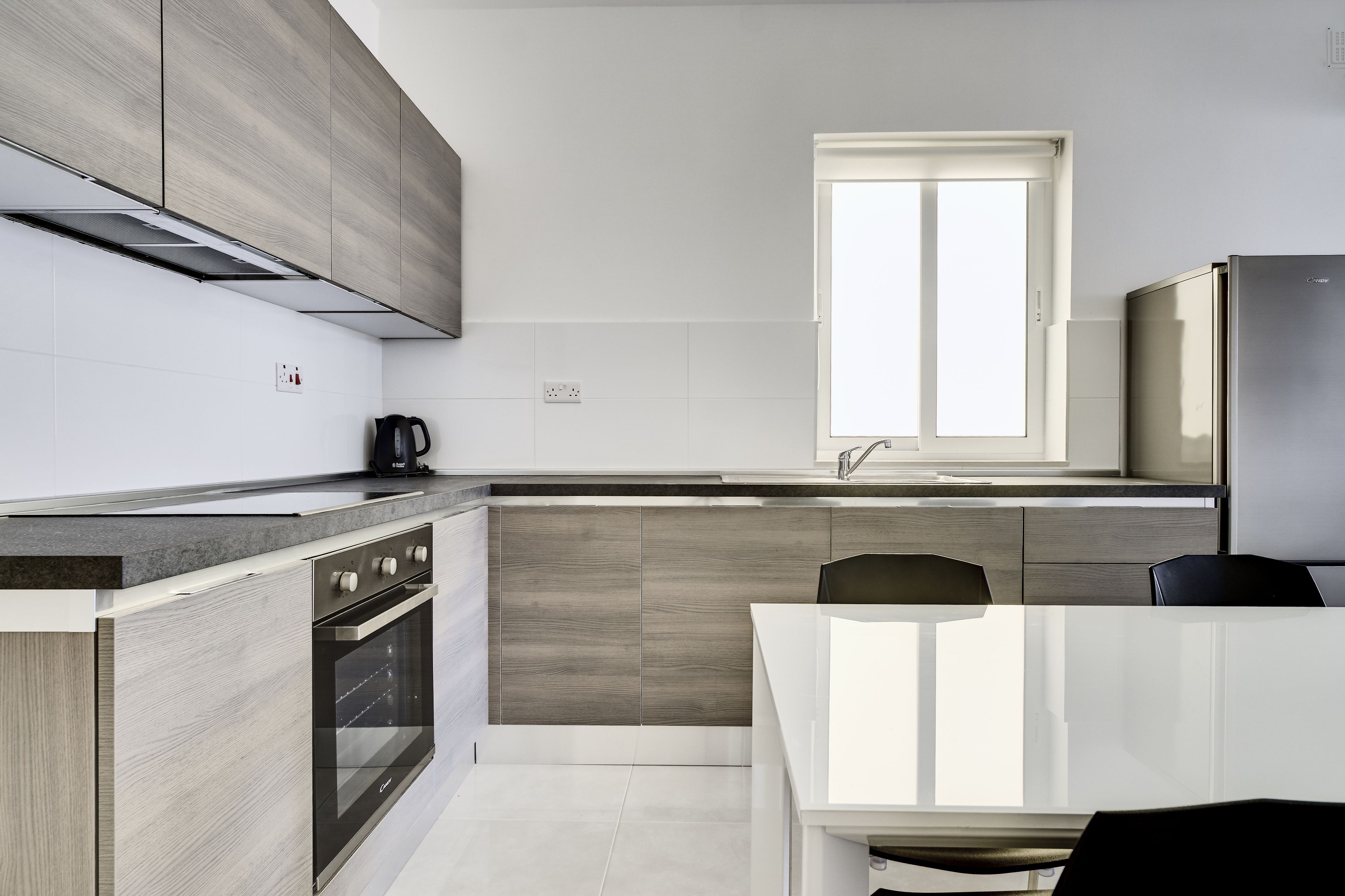 A modern kitchen with a built-in oven, a coffee maker, and a window above the sink.