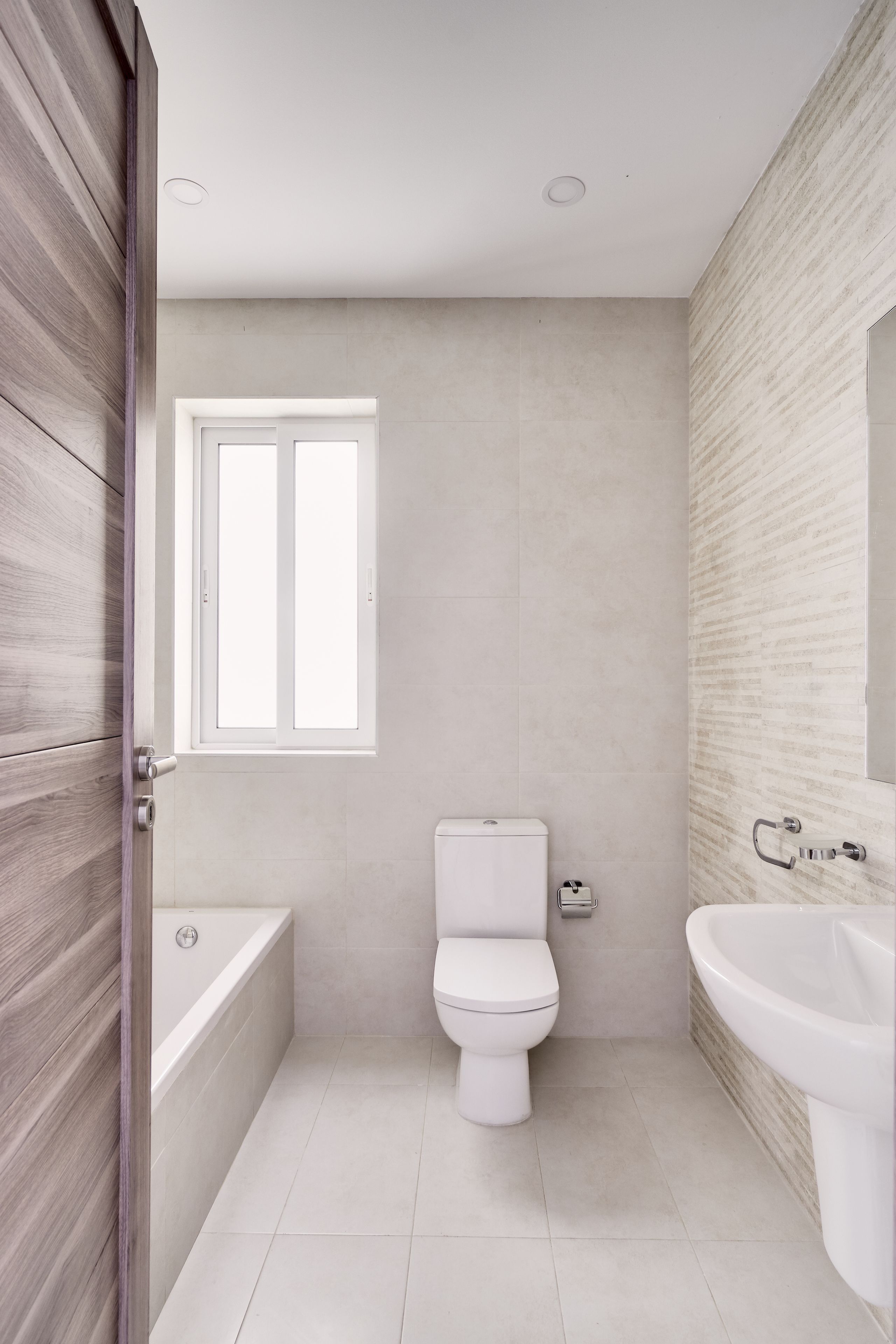 A modern bathroom with a toilet, bathtub, and sink.