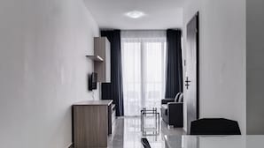 A modern, minimalist hotel room with a large bed, a desk, and a chair. - The Village Apartments (St. Paul's Bay)