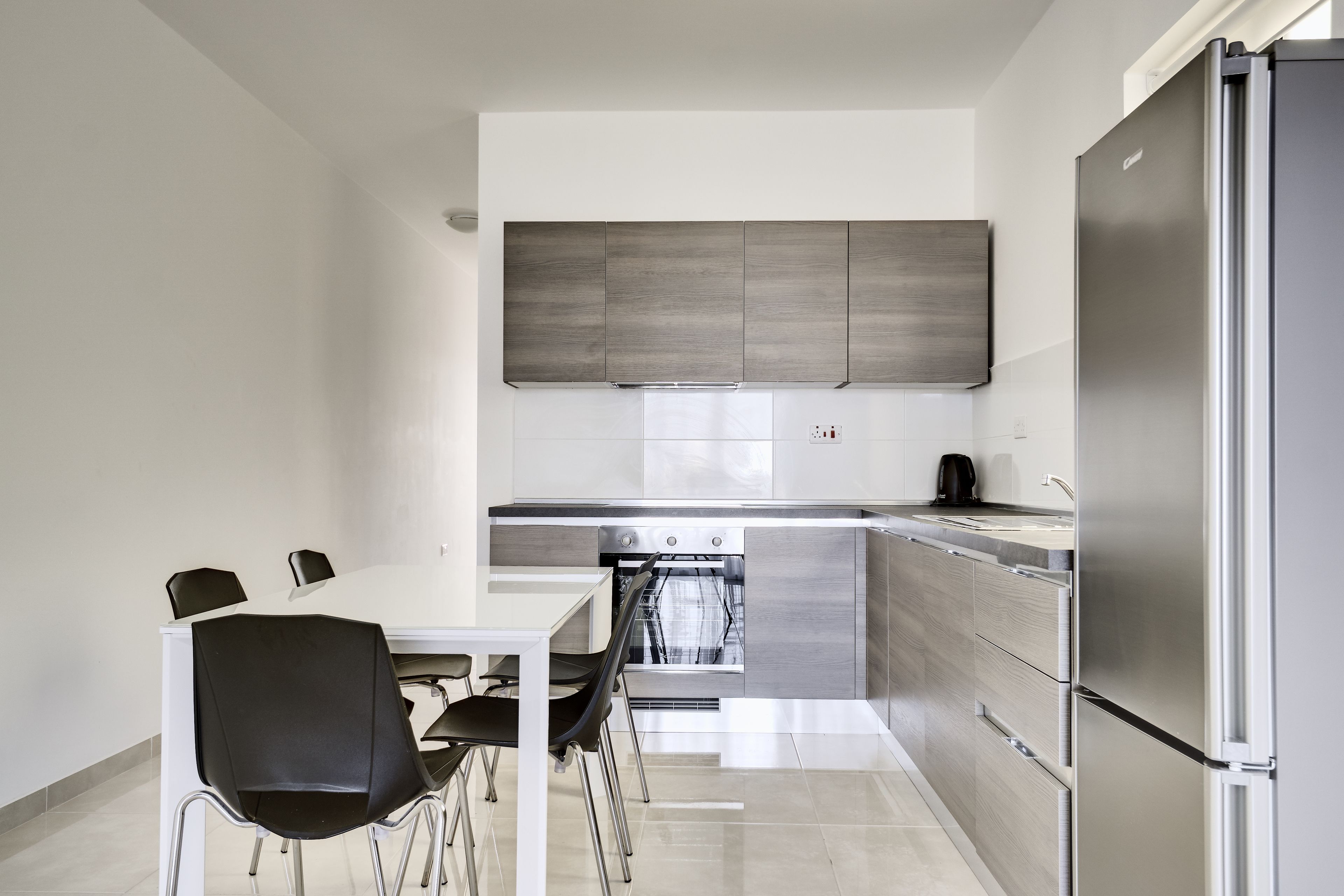 A modern kitchen with a dining area, stainless steel appliances, and a large refrigerator.