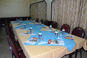 A conference room with a long table set for meetings, equipped with water bottles, papers, and pens.