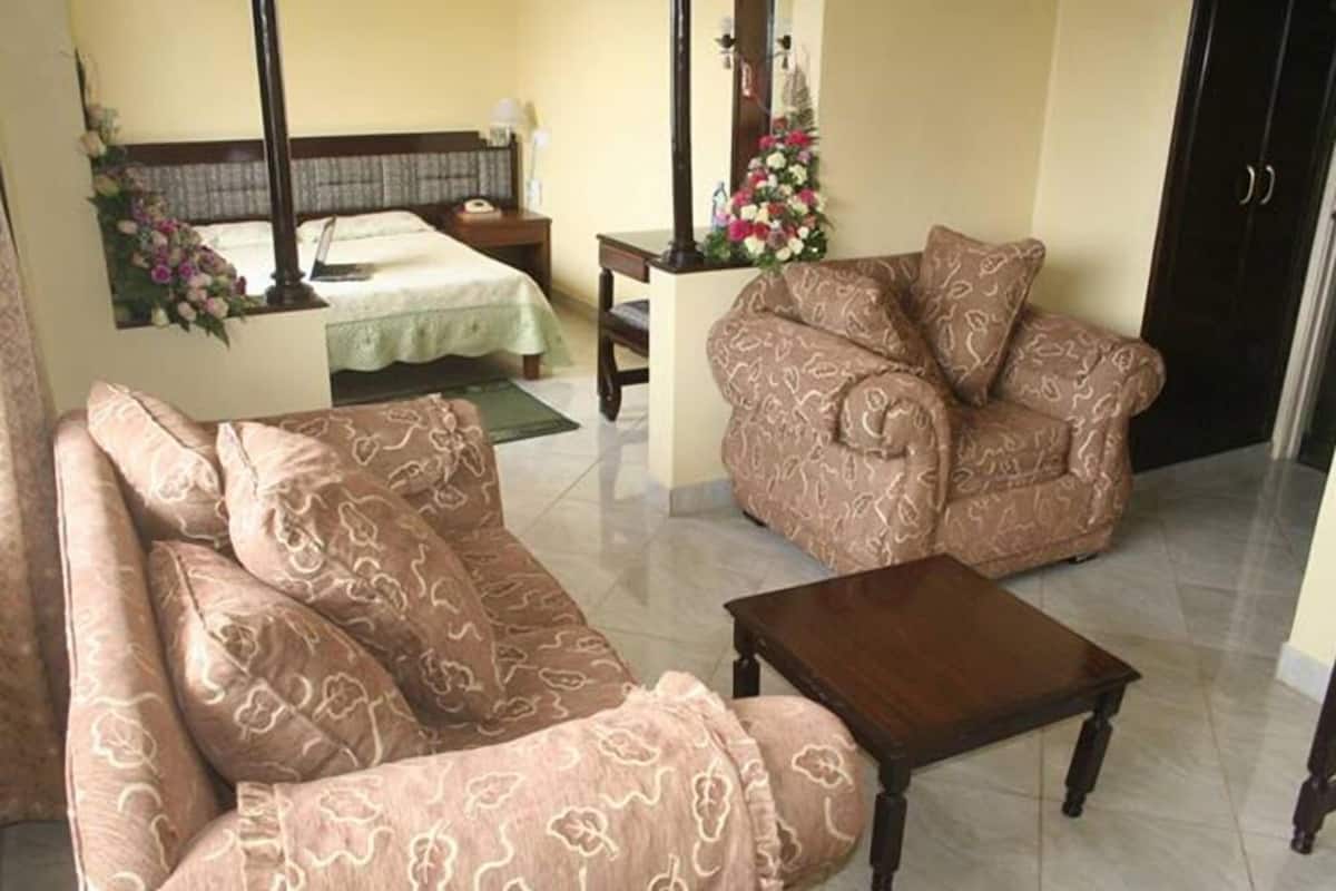 A room with a bed, a sofa, a chair, and a small table.