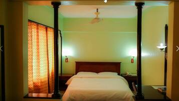 Une chambre d’hôtel équipée d’un lit, de tables de chevet, d’un téléphone et d’un ventilateur de plafond.