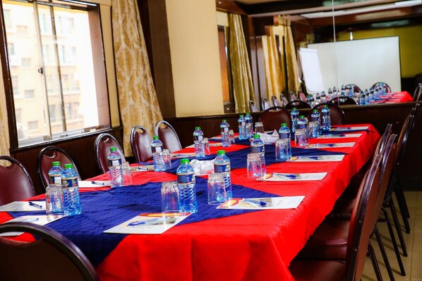 A conference room with a long table, chairs, water bottles, and a whiteboard.