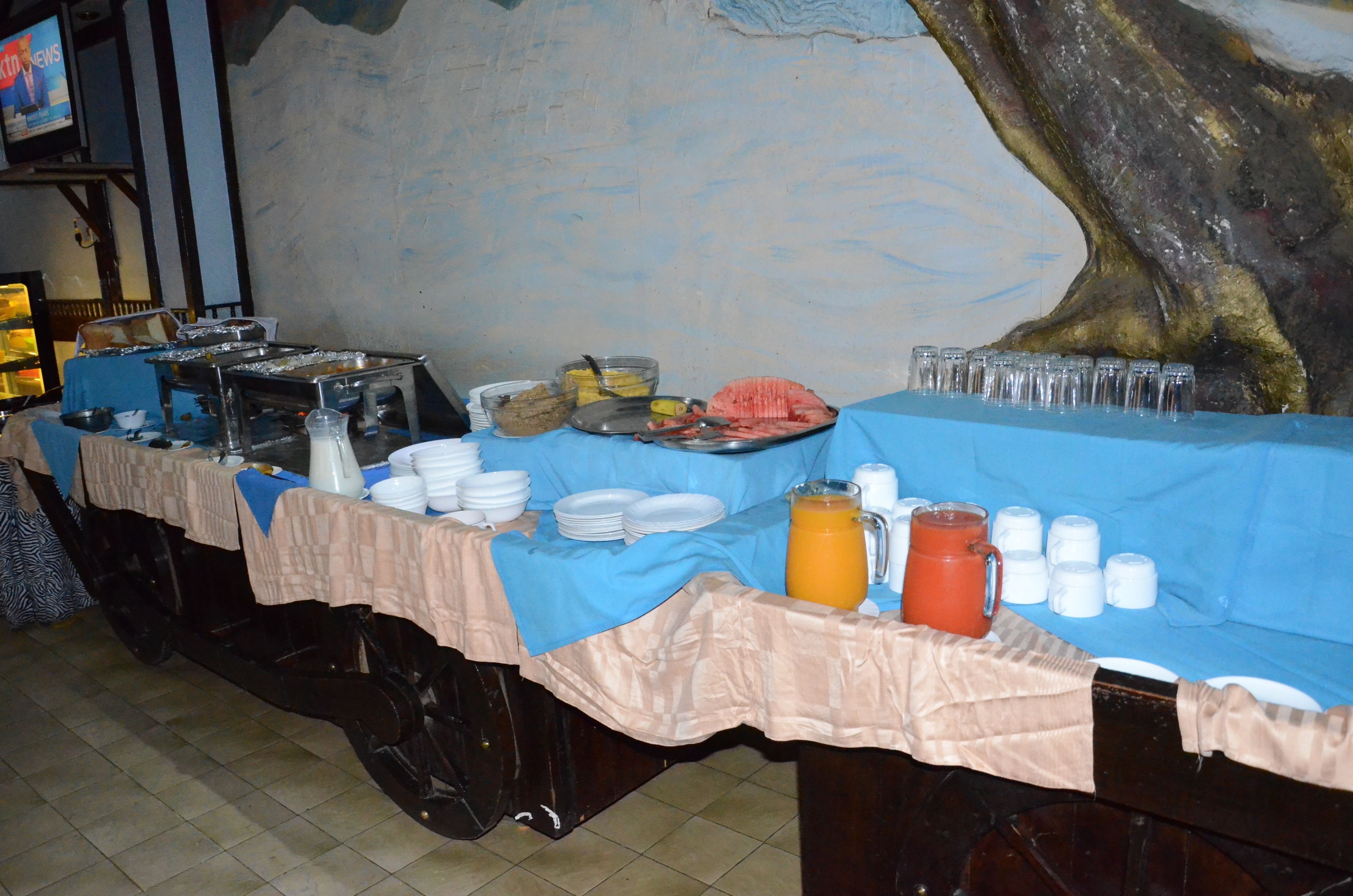 A buffet table with various food items and drinks, covered with a blue tablecloth.