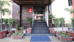 A hotel entrance with a dark wooden facade, a red OYO sign, and potted plants on either side of the steps. - OYO 1673 Hotel MM Yellowuds (Amritsar)