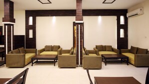 A spacious living area with sofas and a coffee table, a wooden accent wall, and recessed ceiling lighting. - OYO 1673 Hotel MM Yellowuds (Amritsar)