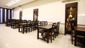 A dining area with multiple wooden tables and chairs, arranged in rows. - OYO 1673 Hotel MM Yellowuds (Amritsar)