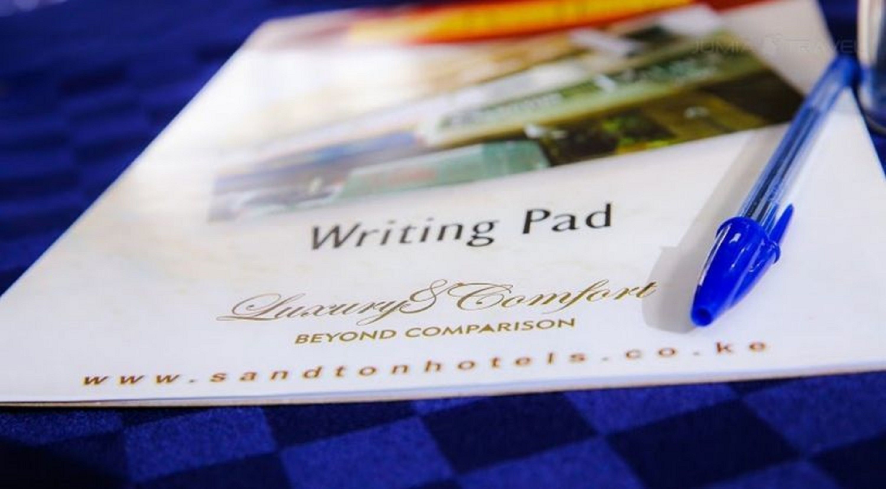 A writing pad with the text "Writing Pad Luxury & Comfort Beyond Comparison" and a website address.