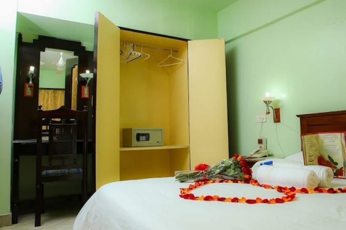 Quarto de hotel com cama, mesa de cabeceira com um livro, abajur e guarda-roupa.