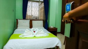 Een hotelkamer met een bed, een groene plaid en een handdoekopstelling op het bed.