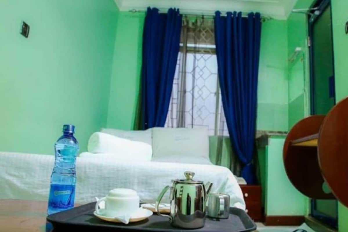 A room with a bed, a tray with a water bottle, a cup, and a kettle.
