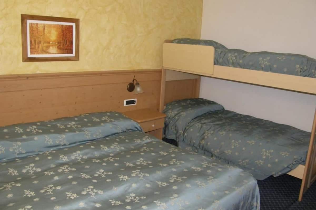 A room with bunk beds, a bedside table, a lamp, and a framed picture on the wall.