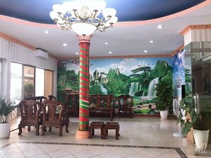 A lobby with a large mural of a waterfall, wooden furniture, and a distinctive striped column. - Cong Doan Hotel Vung Tau (Ho Chi Minh City)