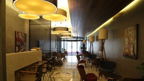 Een modern interieur met een lange receptiebalie, meerdere zithoeken en hanglampen.