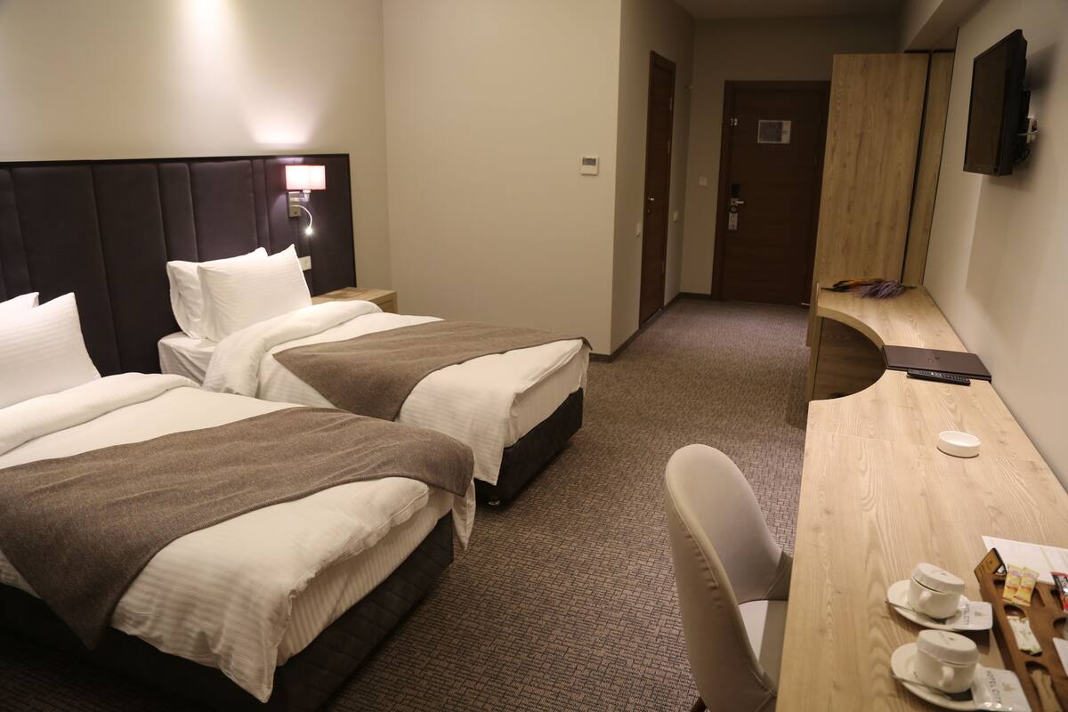 Een hotelkamer met twee bedden, een bureau, een stoel, een televisie en een deur.