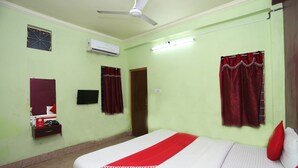 A room with a bed, a ceiling fan, an air conditioner, a mirror, and a door. - OYO 4108 near Kalinga Hospital (Bhubaneshwar)