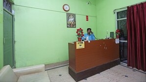 A reception area with a wooden desk, a clock, and a framed picture on the wall. - OYO 4108 near Kalinga Hospital (Bhubaneshwar)