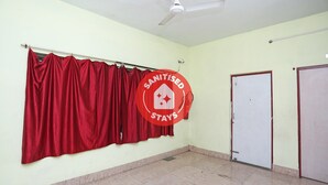 A room with a red curtain, a ceiling fan, and a sign indicating the room is sanitized. - OYO 4108 near Kalinga Hospital (Bhubaneshwar)