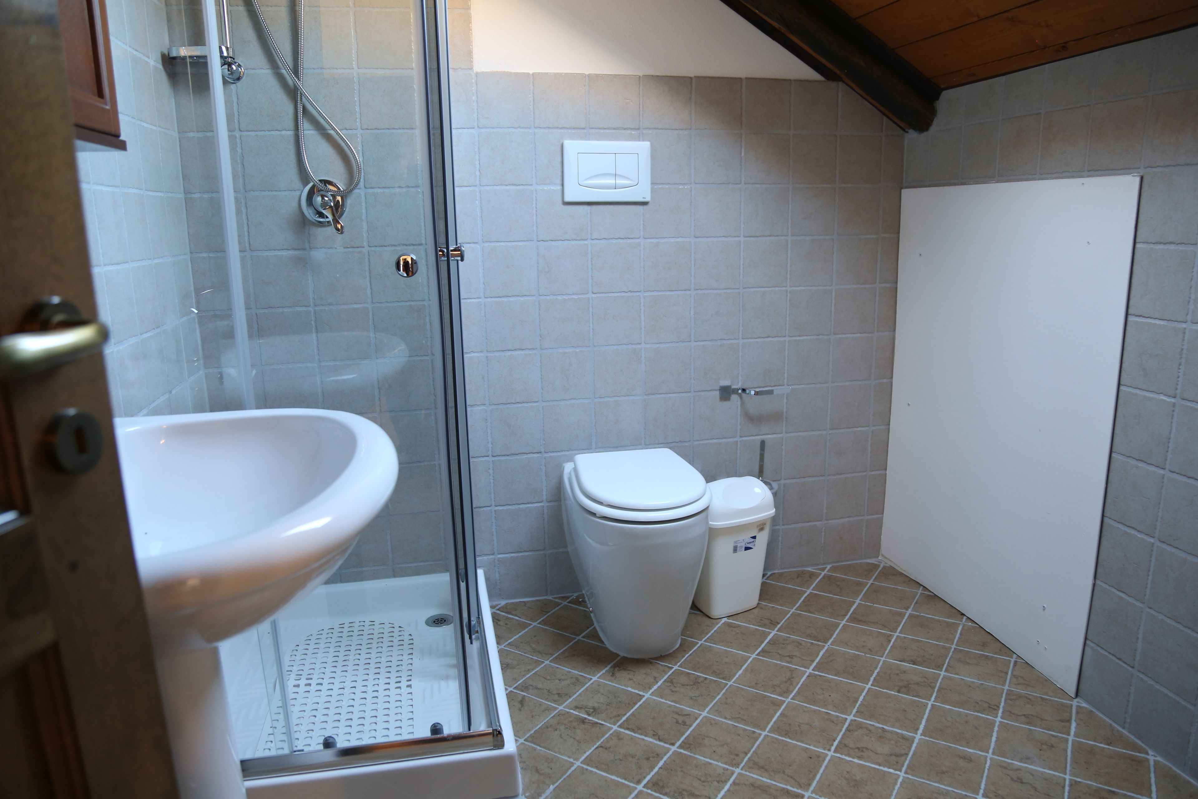 Un bany amb dutxa de vidre, un lavabo, un vàter i un cendrer.