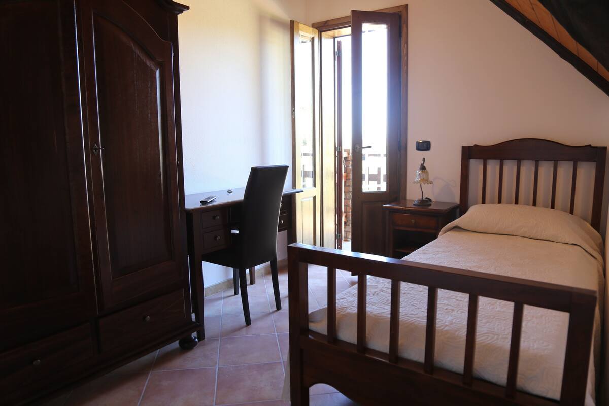 Ein Schlafzimmer mit einem hölzernen Bett, einem Schreibtisch mit Stuhl und einem Kleiderschrank.