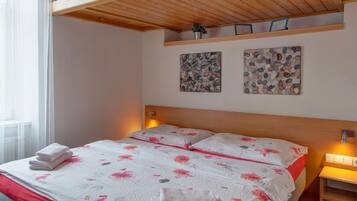Una camera da letto con una cuccetta a castello, un letto con biancheria da letto floreale, un comodino con una lampada e una finestra con tende.