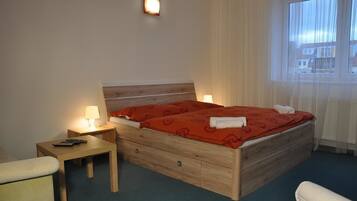 Une chambre d’hôtel avec un lit en bois, deux tables de chevet avec des lampes, une chaise et une fenêtre avec des rideaux.