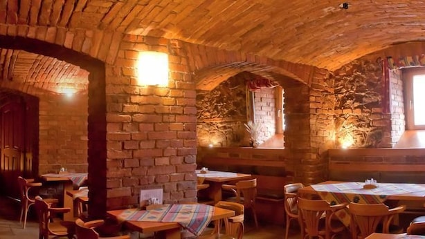 A rustic interior with stone walls, wooden tables, and chairs. - Penzion U Vlka (Ceske Budejovice)