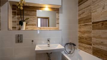 A bathroom with a white sink, mirror, and wooden wall paneling.
