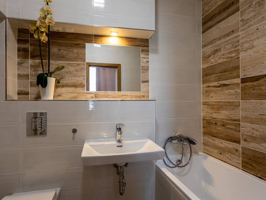 A bathroom with a white sink, mirror, and wooden wall paneling.