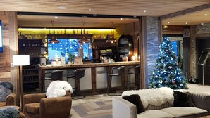 Zona relaxant i acollidora amb bar, sostre de fusta i un arbre de Nadal.