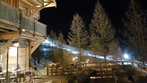 Un edifici de fusta amb un balcó, zona d'estar a l'exterior i vistes a una muntanya nevada.