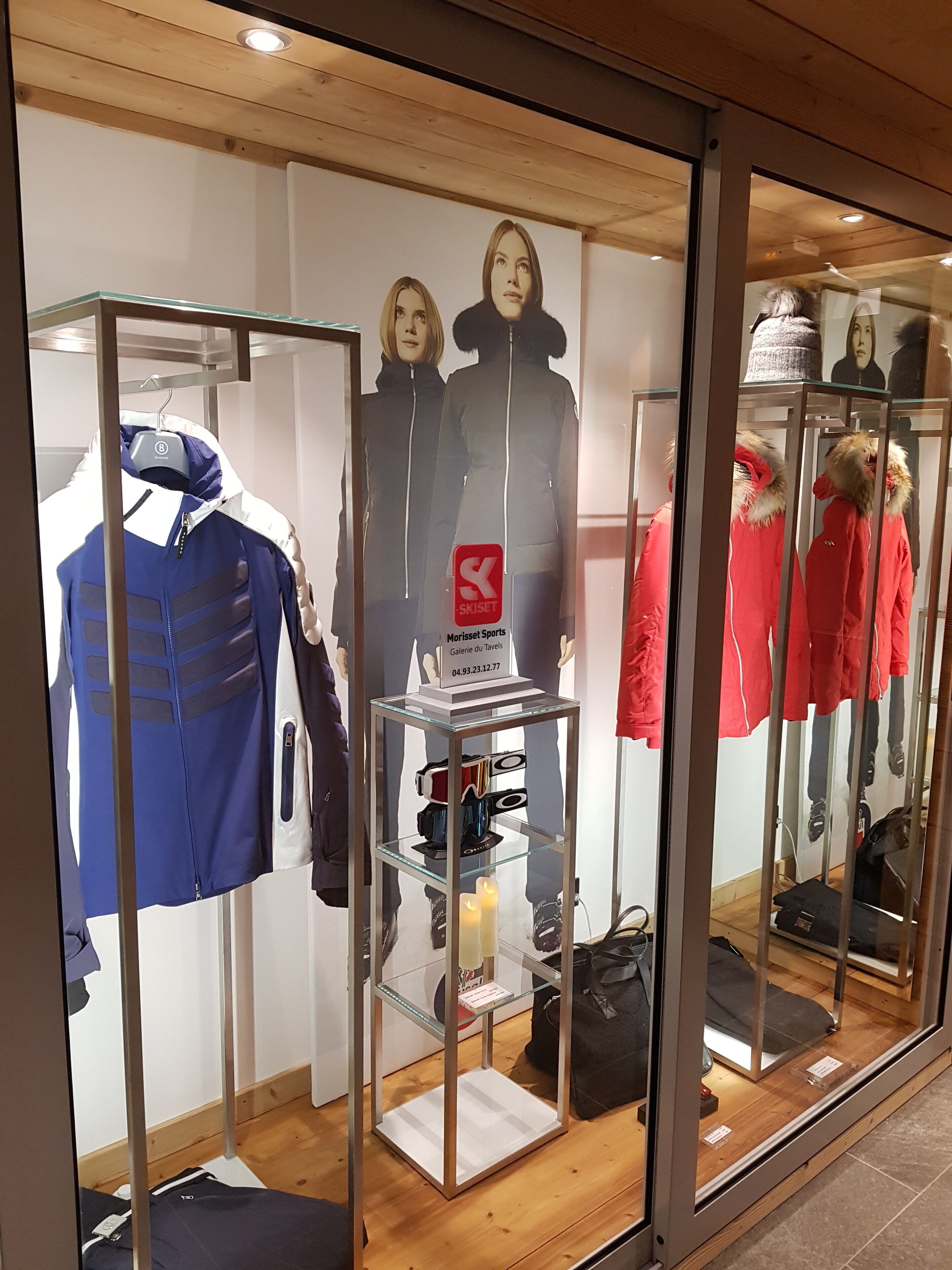 Un magasin de vêtements où des mannequins présentent des vestes d’hiver et une étagère expose du matériel de ski.