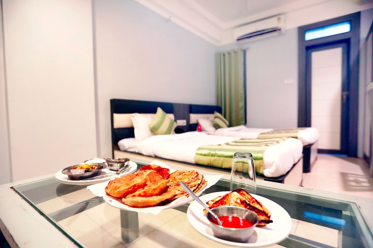 A hotel room with a bed, a glass table with food, and a view of the hallway.