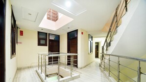 A modern interior with a glass railing, a skylight, and a marble floor. - OYO 8278 Supremo (Chandigarh)