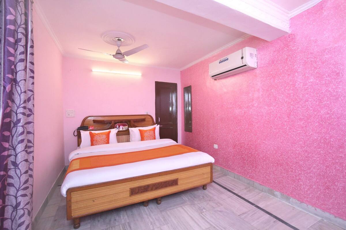 A bedroom with a bed, a ceiling fan, an air conditioning unit, and a wooden headboard.