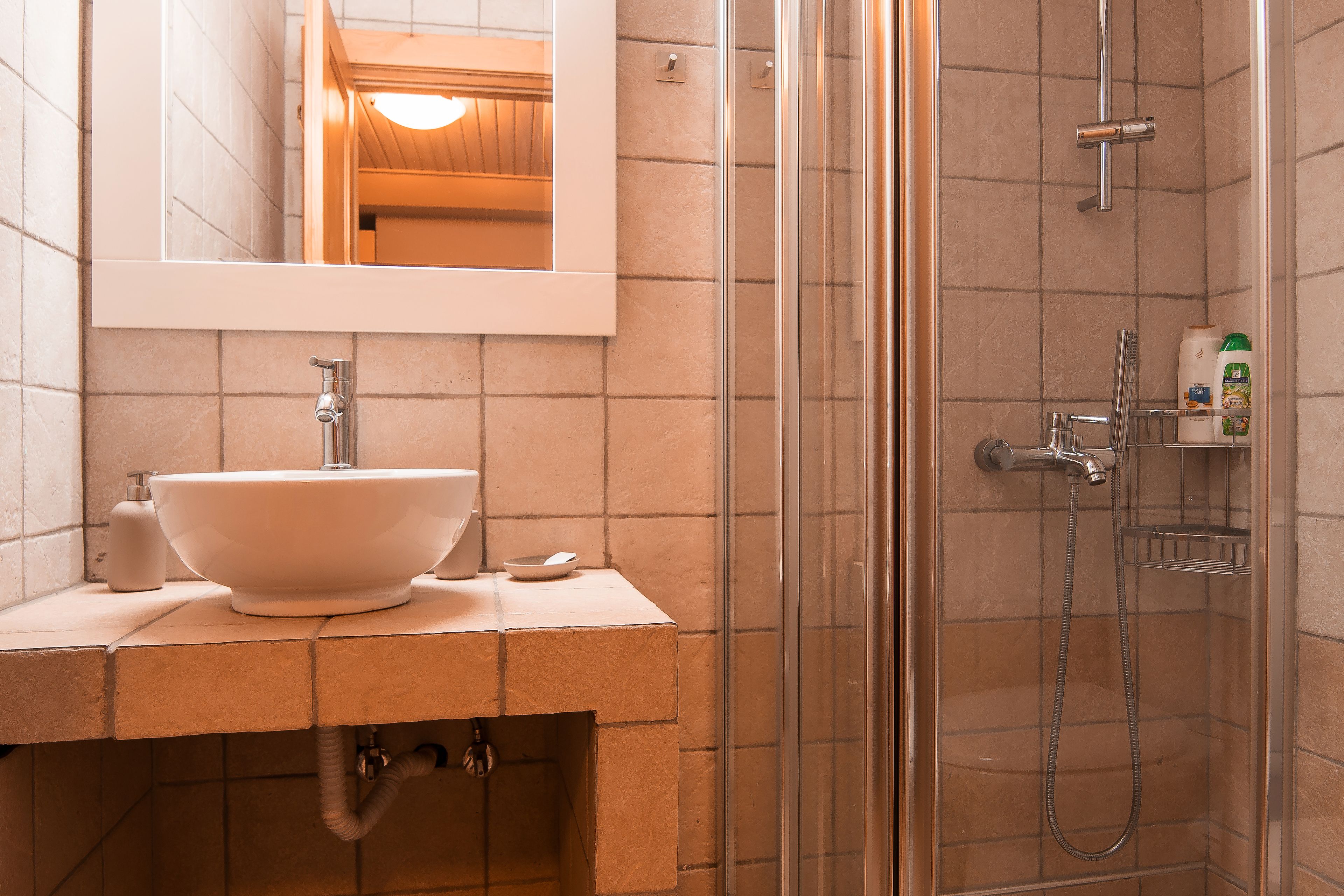 A bathroom with a large sink, a mirror, and a glass-enclosed shower.