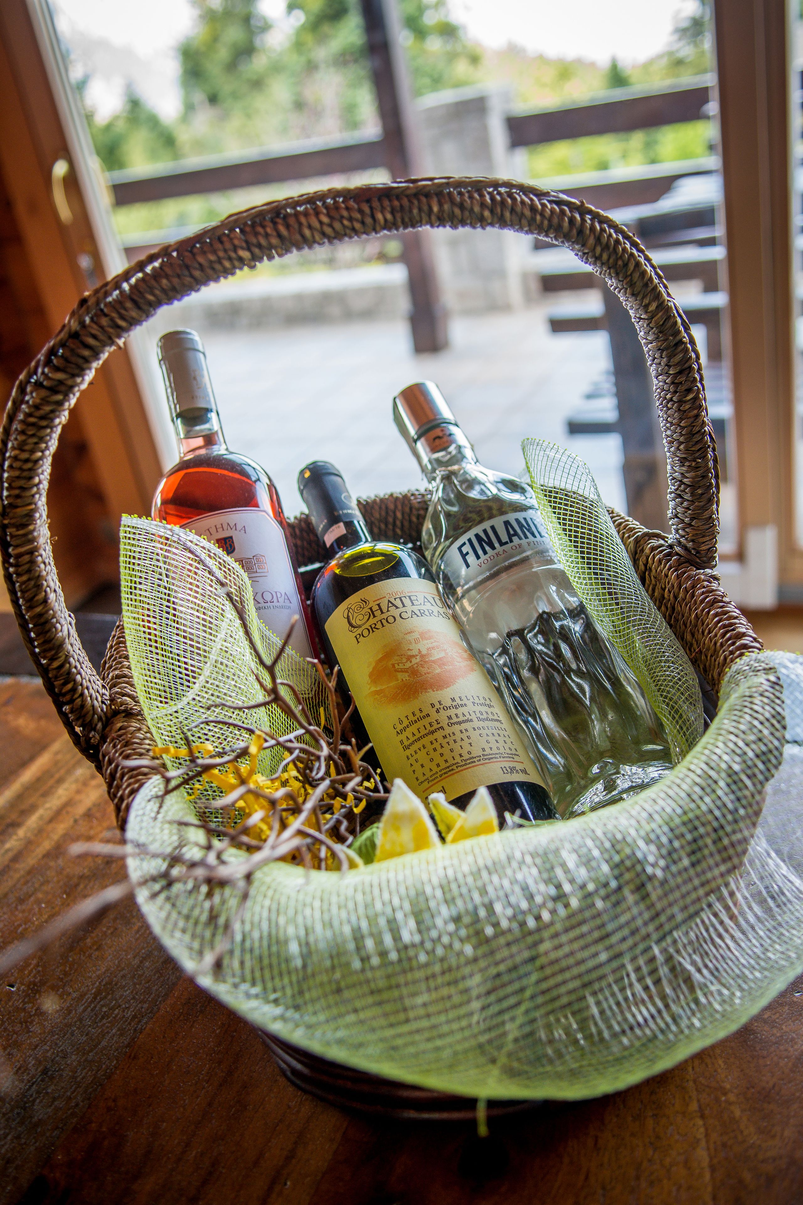 A wicker basket containing several bottles of alcohol, including a bottle of Finlandia vodka, on a wooden table.