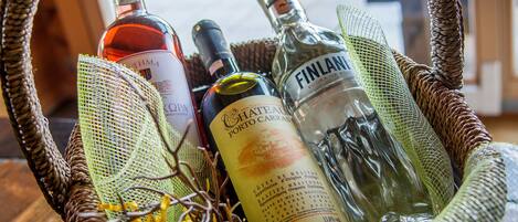 A wicker basket containing several bottles of alcohol, including a bottle of Finlandia vodka, on a wooden table.