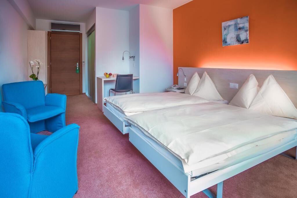Una habitación de hotel con una cama, un escritorio, una silla y una mesita.