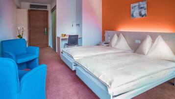 Una habitación de hotel con una cama, un escritorio, una silla y una mesita.