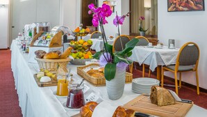 Un bufé de desayuno con pan, bollería, frutas y salsas.