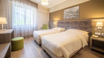 Una habitación de hotel con dos camas, un escritorio, una silla y una lámpara.