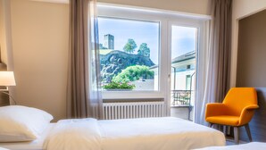 Habitación de hotel con dos camas, una ventana con vistas a un castillo y una silla naranja.