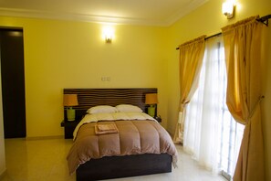 Ein Schlafzimmer mit einem Bett, Nachttischen und einem Fenster mit Vorhängen.