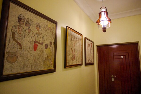 Un couloir avec trois œuvres d’art encadrées accrochées au mur et une porte en bois.