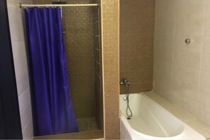 Ein Badezimmer mit Dusche, Badewanne und einem blauen Duschvorhang.