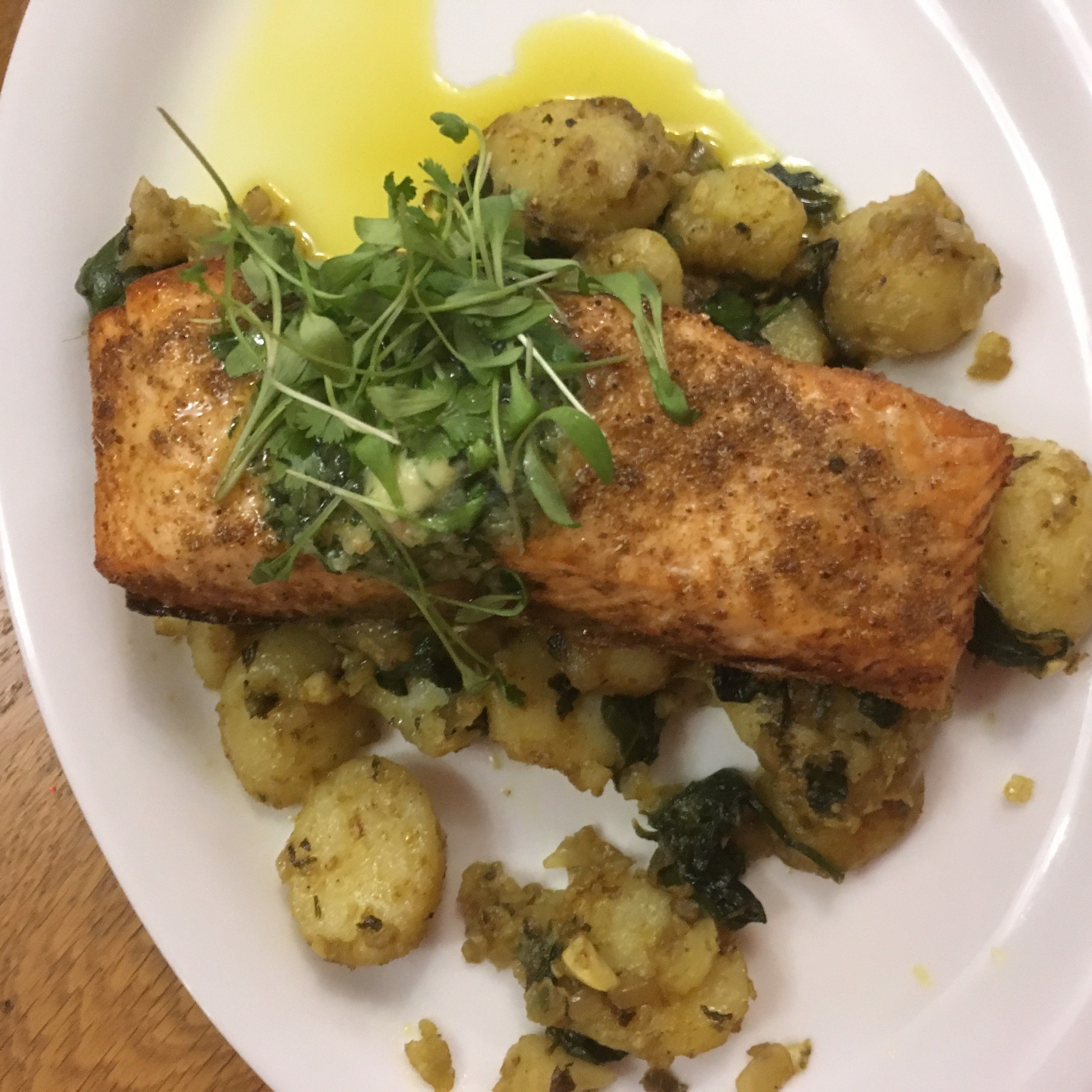 Une assiette contenant un morceau de poisson grillé, des pommes de terre et des légumes verts.