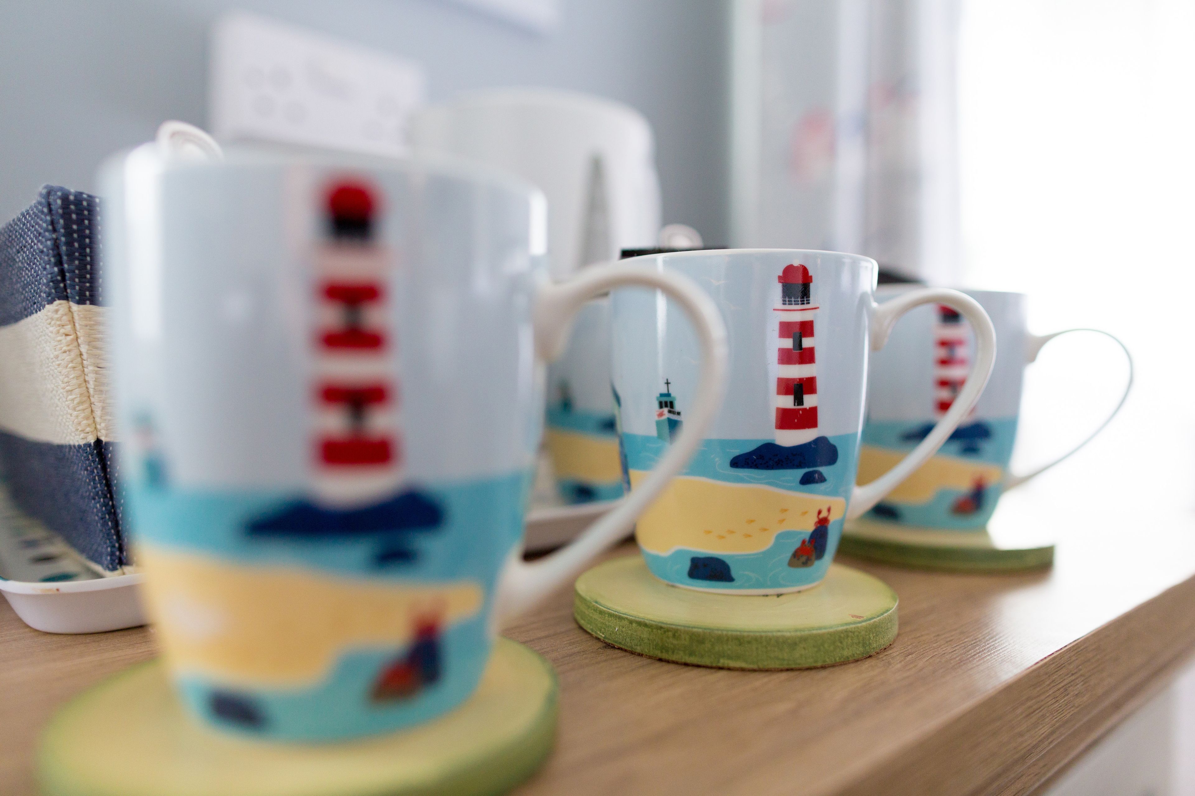 Three white mugs with red and blue designs on a wooden surface.